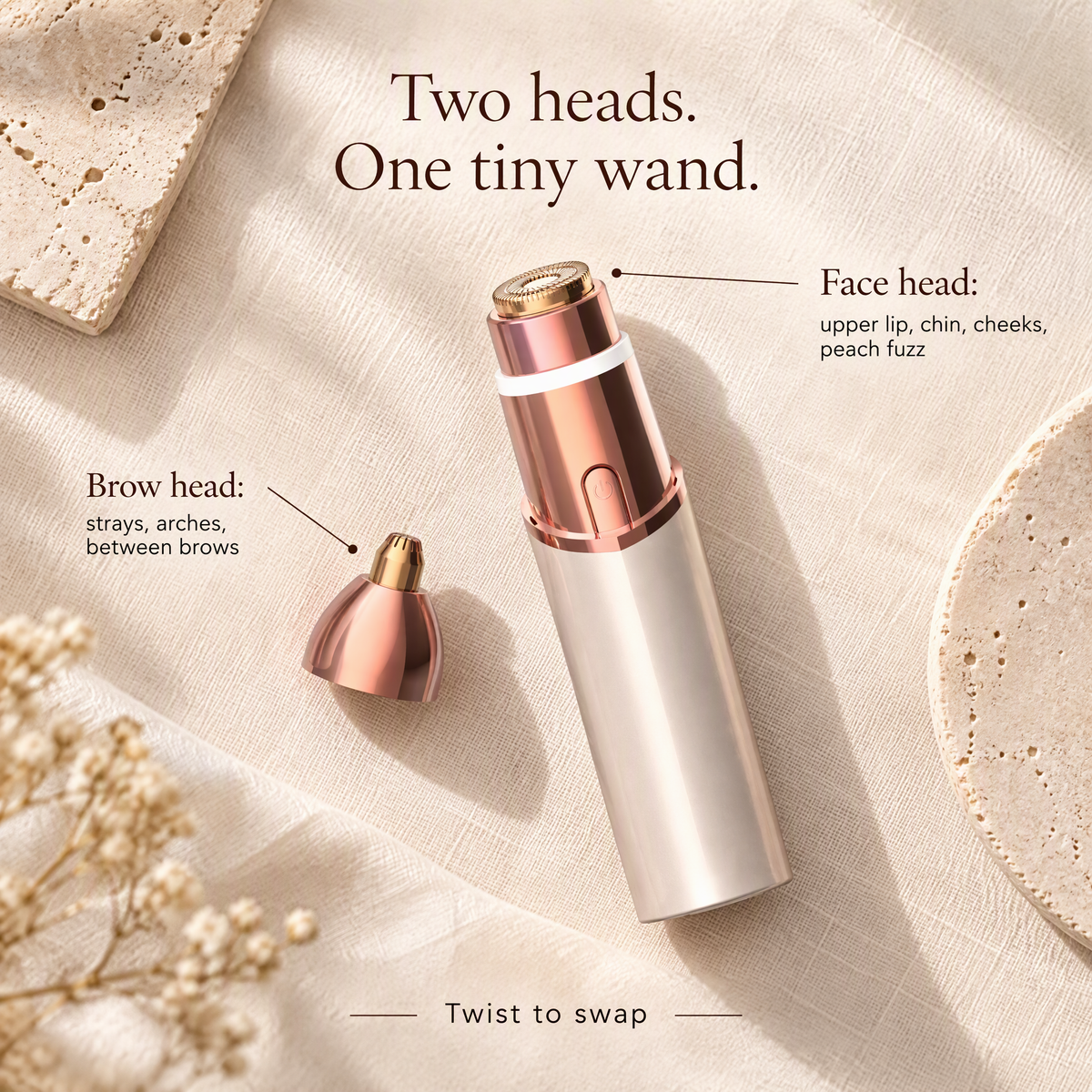 A rose gold and silver electric eyebrow grooming wand with its detachable brow head accessory, styled on a textured beige fabric background with decorative stones and text explaining the features.
